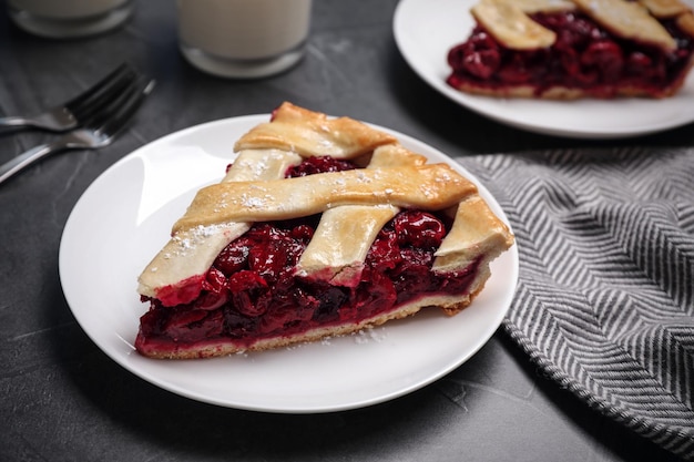 Slice of delicious fresh cherry pie on grey table closeup