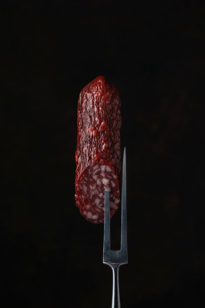 Slice of dried sausage on a meat fork