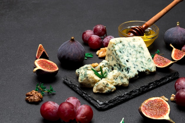 Slice of French Roquefort cheese and fruits on stone board