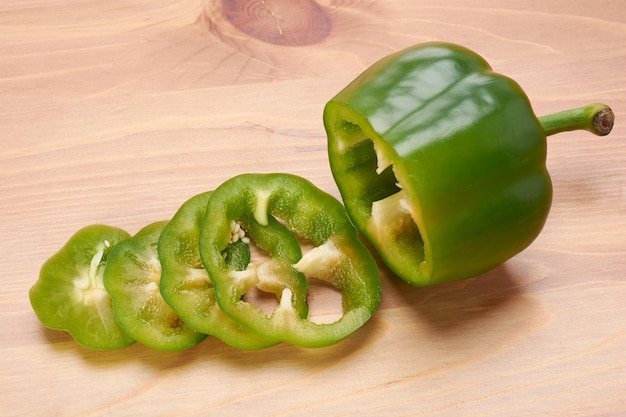 Slice green sweet pepper on table