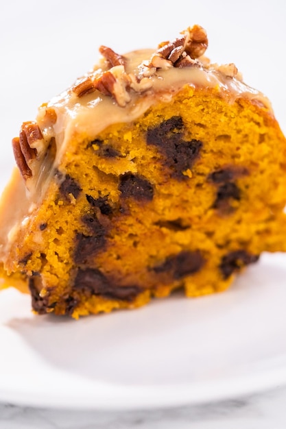 Slice of homemade chocolate pumpkin bundt cake with toffee glaze on a  plate.