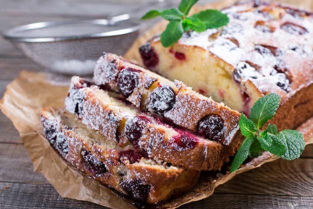 Slice of homemade cranberry cake with cherries powdered sugar and mint