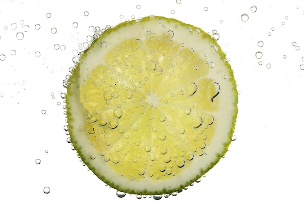 Slice of lime in the water with bubbles, isolated on white