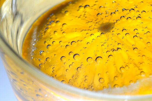 A slice of orange covered with bubbles lies in a glass of sparkling water. Close-up.