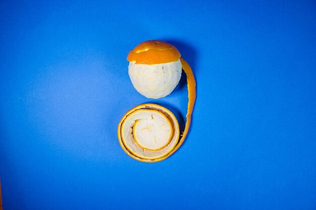 Slice orange in a peel on a blue background