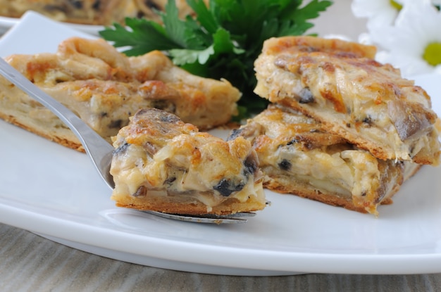 Slice of pie with mushrooms and cream sauce on a fork