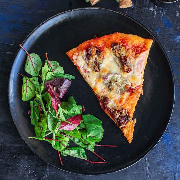 slice of pizza and salad leaves in a plate