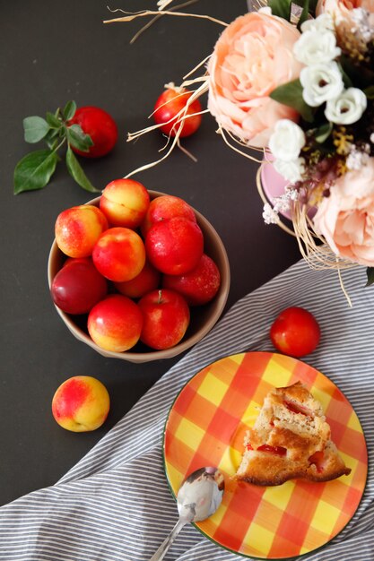 Slice of plum pie on plate. Summer recipe. Plums and flowers still life. 