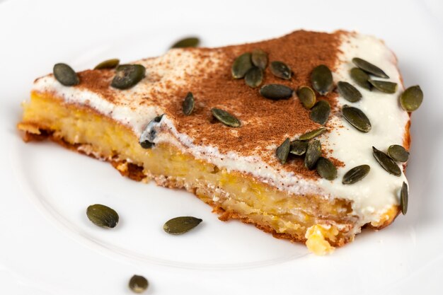 Slice of a pumpkin pie with seeds on a white plate close-up