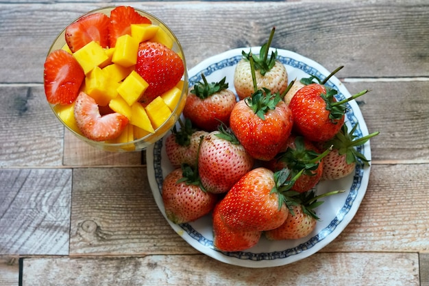 Slice of ripe mango and strawberry in a cocktail glass and fresh strawberry on the plate