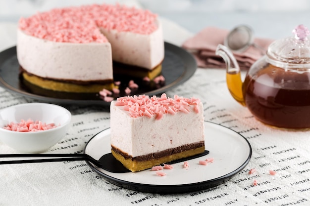 Slice of strawberry vanilla cheesecake decorated with pink chocolate chips on plate