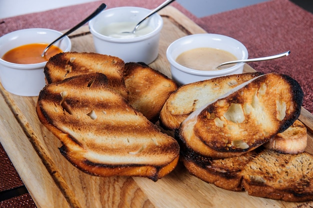 Slice of toast roasted in breaded with cheese and sesame slipped in a sauce on a wooden board