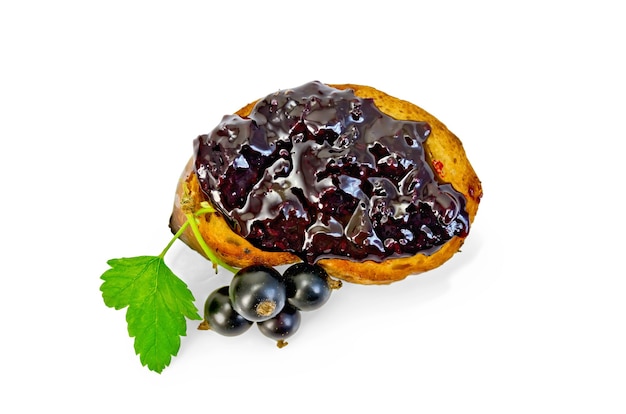 A slice of toast with jam from blackcurrant, branch with berries and leaves of black currant isolated on white background top