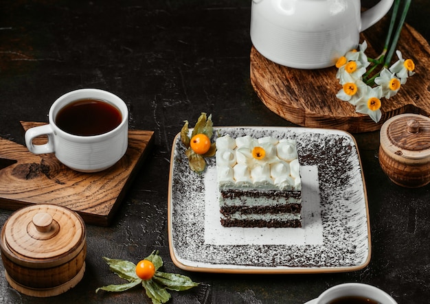 A slice of white creamy cake with chocolate on a wooden board