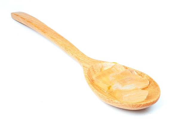 Sliced aloe vera flesh rests on a wooden spoon on white backgroundcloseup