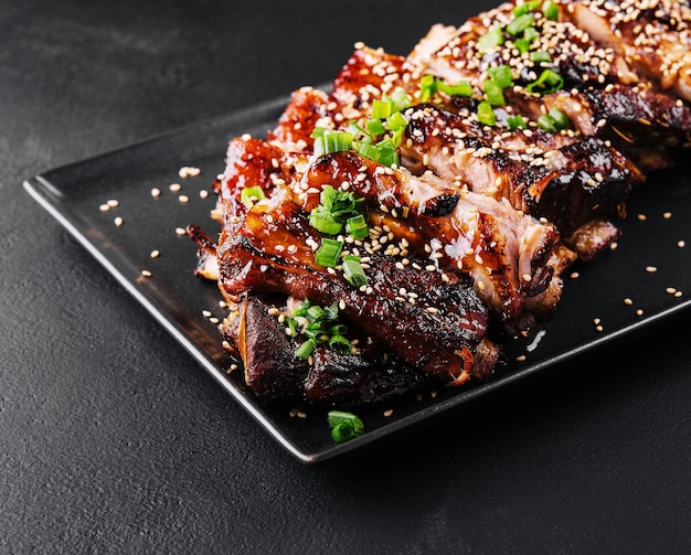 Sliced BBQ pork ribs on black plate