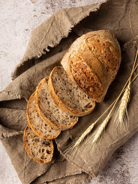 Sliced bread in burlap. Next to it are ears of wheat. Background structural