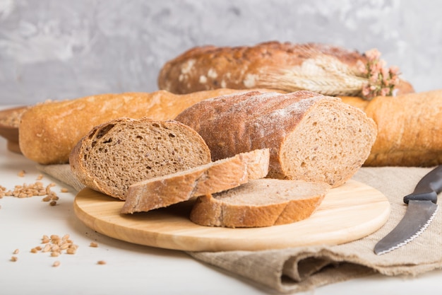 Sliced bread with different kinds of fresh baked bread on a white wooden wall. side view, selective focus.