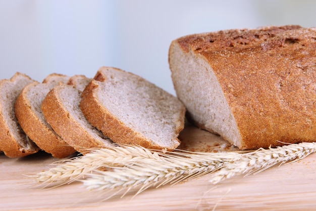 Sliced bread on wooden board on bright background