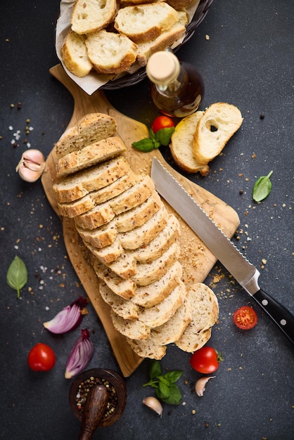 Sliced bread on wooden cutting board on dark table