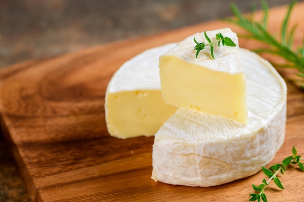 Sliced Camembert Cheese with thyme on wood plate Camembert is a moist soft creamy