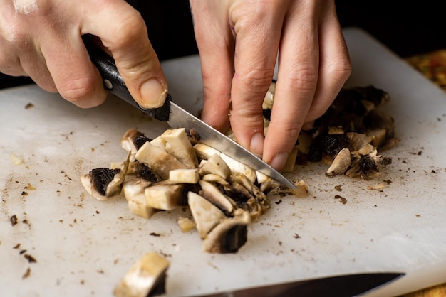 Sliced champignon mushrooms on a cutting board Women's hands cut mushrooms with a knife