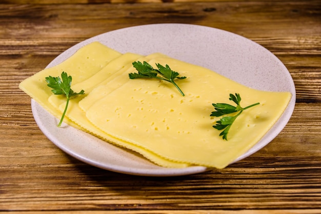 Sliced cheese and parsley in ceramic plate on rustic wooden table