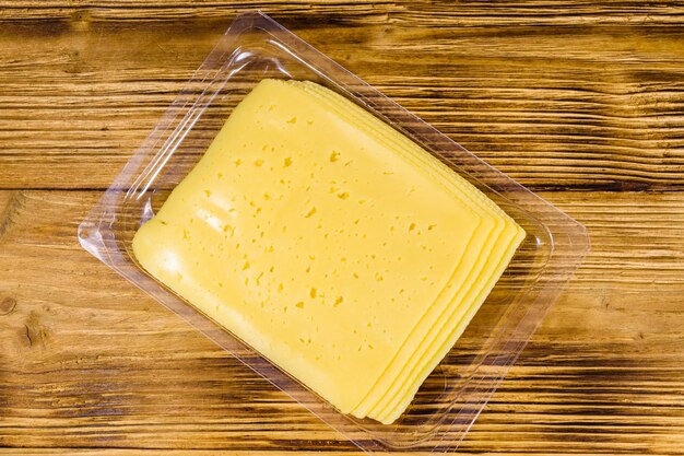 Sliced cheese and parsley in plastic container on rustic wooden table Top view