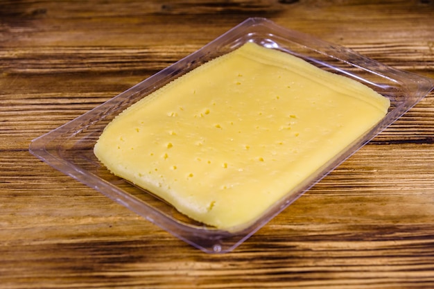 Sliced cheese and parsley in plastic container on rustic wooden table