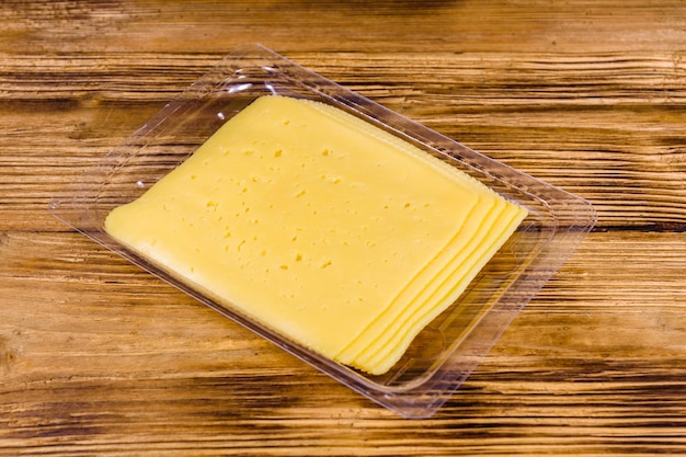 Sliced cheese and parsley in plastic container on wooden table