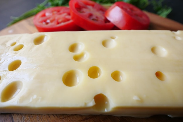 Sliced cheese with holes on a chopping board on table