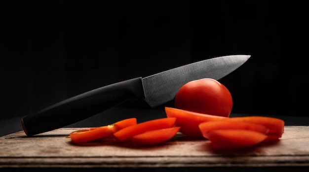 Sliced cherry tomatoes with knife on wooden board on background with copyspace healthy organic pomod