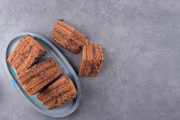 Sliced chocolate cake on a gray tray placed on stone table .