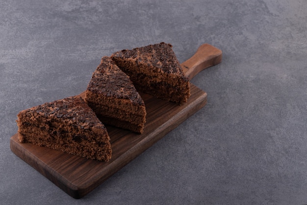 Sliced chocolate cake placed on a stone table .