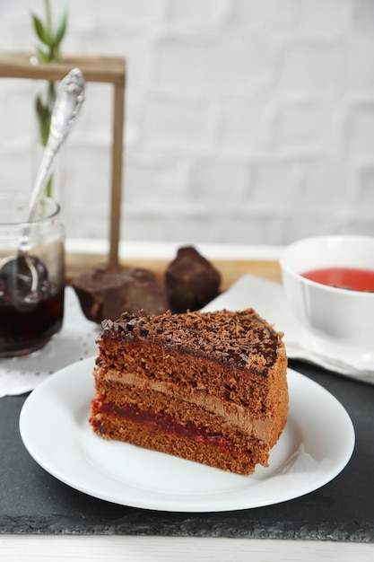 Sliced chocolate cake on wooden table on light background