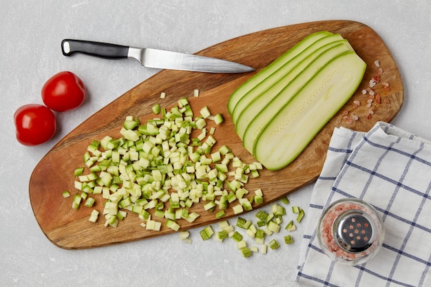 Sliced courgette zucchini vegetables on a wooden cutting board knife tomatoes pink salt and napkin