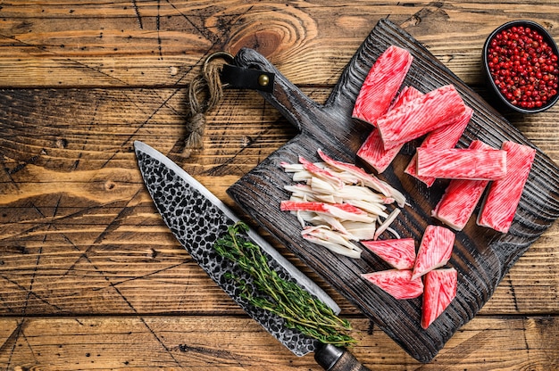 Sliced Crab sticks and meat on a wooden cutting board. wooden background. Top view. Copy space.