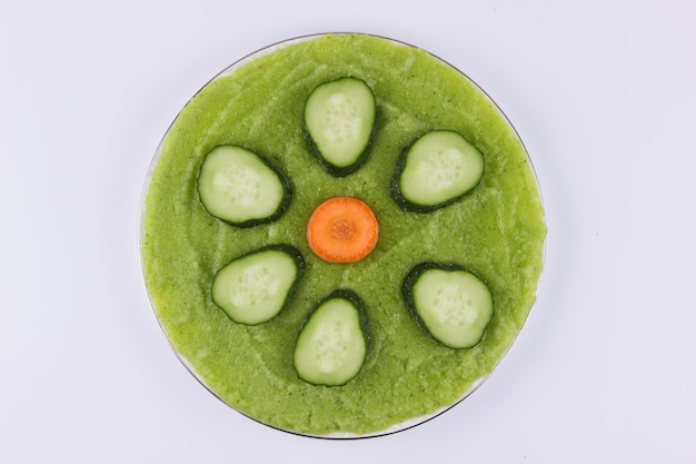 Sliced cucumber and carrot on green puree isolated on white background Closeup of vegetables Healthy food concept