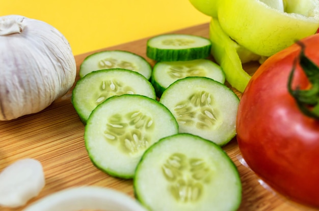 Sliced cucumber tomatoes and garlic on wooden cutting board Healthy food Close up photo