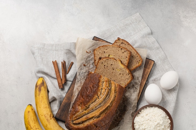 Sliced fresh banana bread with ingredients on light background