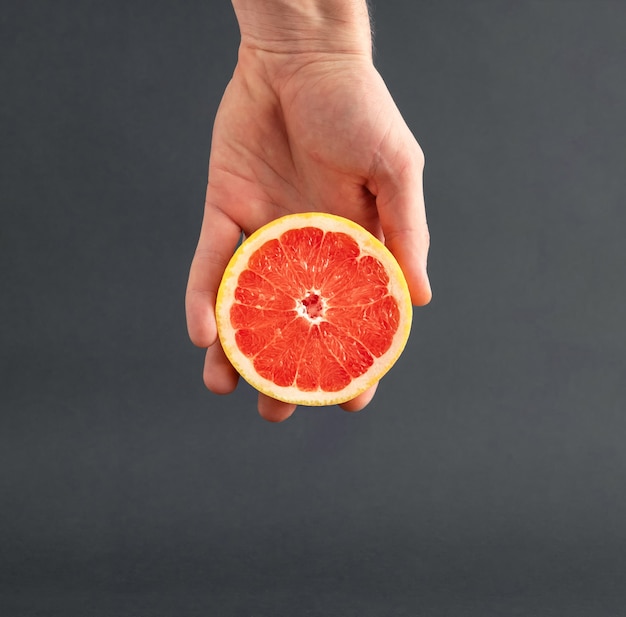 Sliced fresh grapefruit in man's hand.