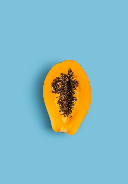 Sliced fresh papaya on blue table. Creative minimalizm