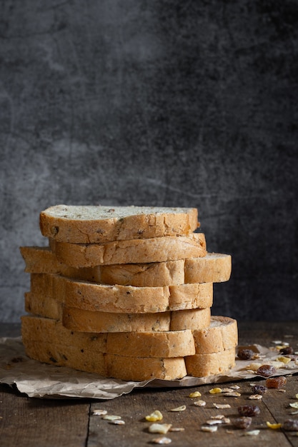 Sliced grain  whole wheat bread on dark rustic wooden background, bio ingredients, healthy food.