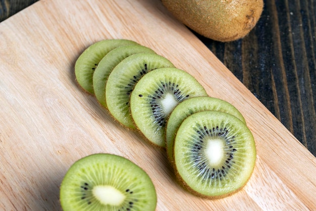 Sliced green kiwi fruit on a wooden board