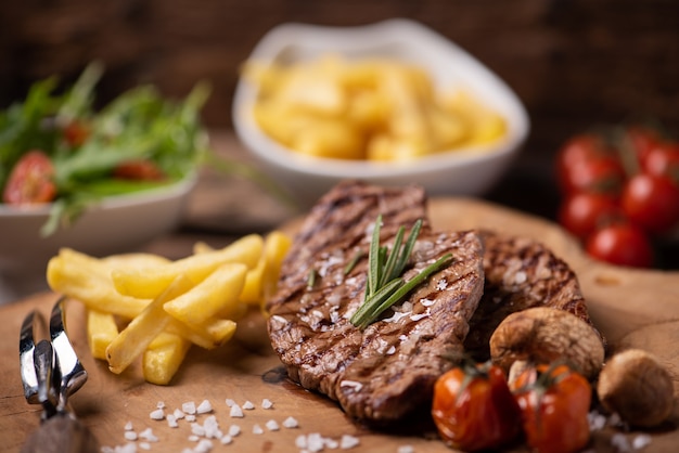 Sliced grilled medium rare beef steak served with fries close up