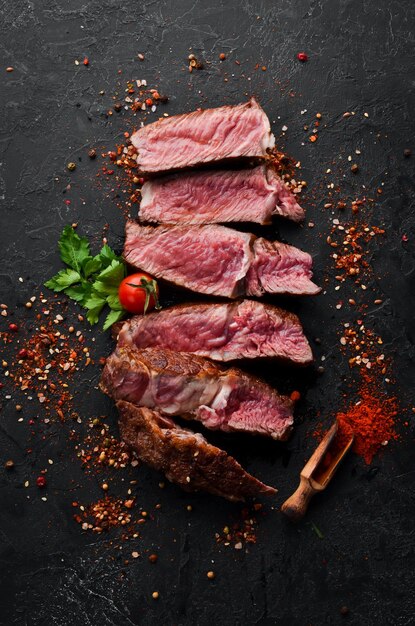 Sliced grilled steak on black stone background Black Angus Top view free space for your text Rustic style