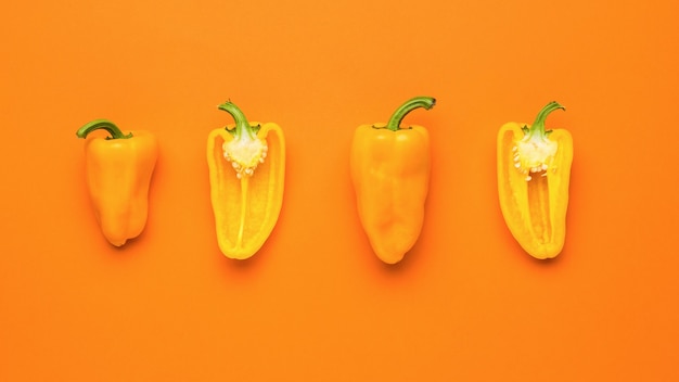 Sliced halves of orange pepper on an orange background. Vegetarian food.