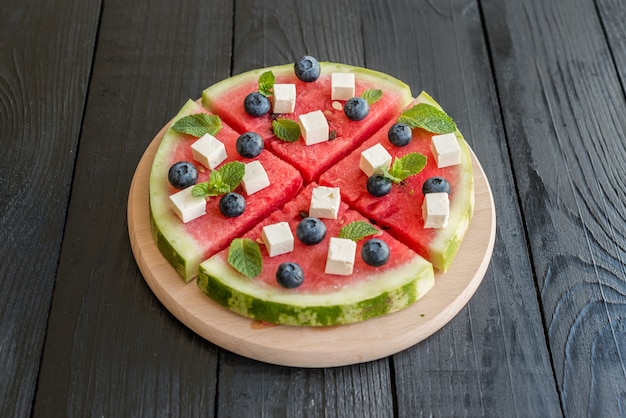 Sliced, juicy watermelon pizza with blueberries and cheese