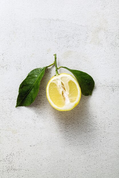 Sliced lemon on a white stone table with leaves.