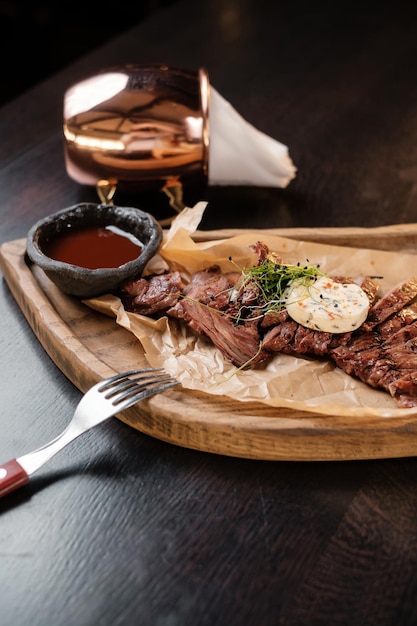 Sliced meat on a wooden board with sauces side view